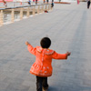 Es ist ein unscharfes, aber mein Lieblingsphoto aus der Zeit in China. Ein Kind, vielleicht ein Mädchen, hat eine leuchtend rote Jacke an, und es läuft, die Arme weit ausgebreitet, an einem See entlang.