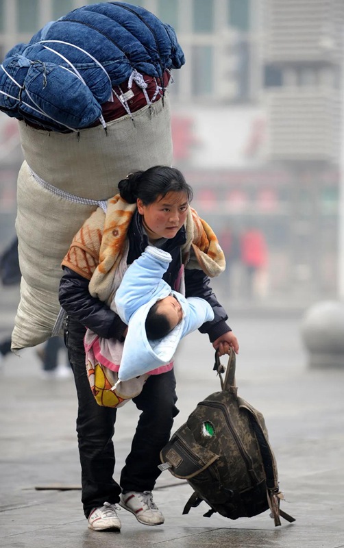 Bamu Yubumu hält ihre Tochter fest, während sie ein riesiges Paket mit Gegenständen auf dem Rücken trägt. Dieses am 30. Januar 2010 aufgenommene Foto berührte die Herzen von Millionen Menschen.