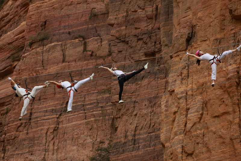 Yoga-Enthusiasten üben auf hoch hängenden Stahlseilen