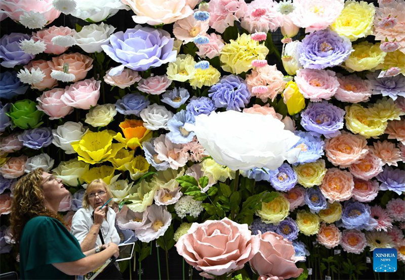 Einkäufer unterhalten sich an einem Stand, der künstliche Blumen präsentiert. (Foto vom 23. April 2024, Xinhua/Deng Hua)